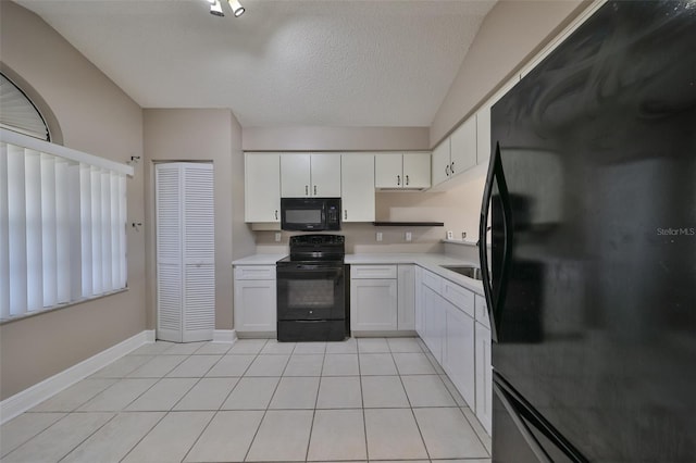 kitchen with black appliances, white cabinets, light tile patterned floors, and a textured ceiling