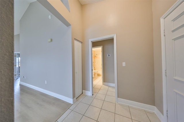 hallway with a towering ceiling and light tile patterned floors