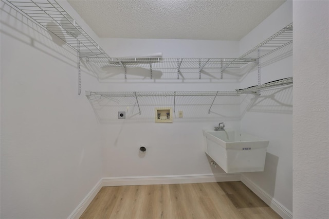 washroom featuring sink, electric dryer hookup, hookup for a washing machine, hardwood / wood-style floors, and a textured ceiling