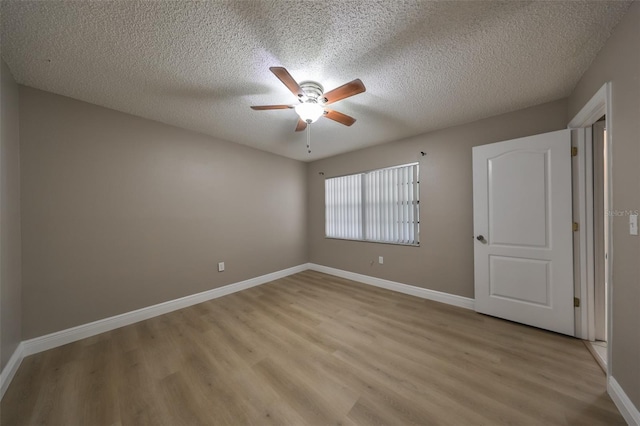 spare room with ceiling fan, light hardwood / wood-style floors, and a textured ceiling