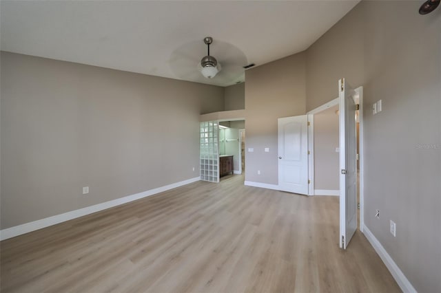 unfurnished bedroom featuring ceiling fan, light wood-type flooring, and a towering ceiling