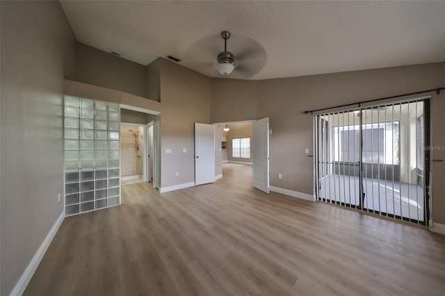 unfurnished room with a textured ceiling, light hardwood / wood-style floors, high vaulted ceiling, and ceiling fan