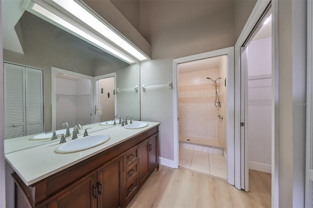 bathroom with hardwood / wood-style floors, vanity, and tiled shower