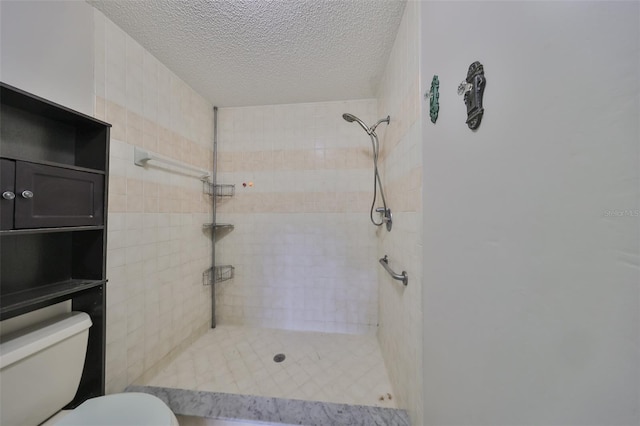 bathroom featuring toilet, a textured ceiling, and tiled shower