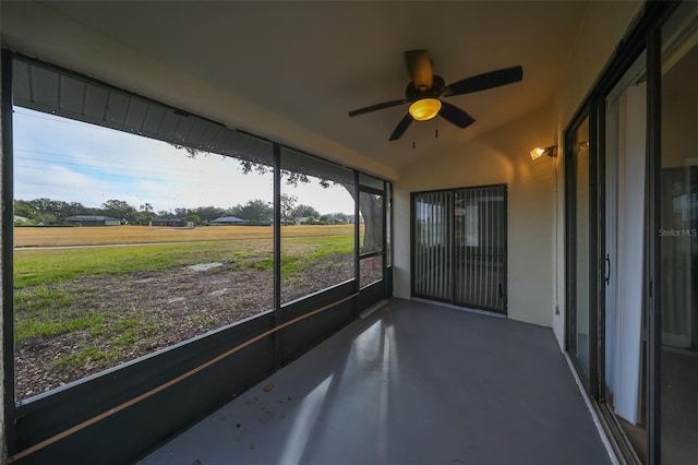 unfurnished sunroom with ceiling fan, a rural view, and lofted ceiling