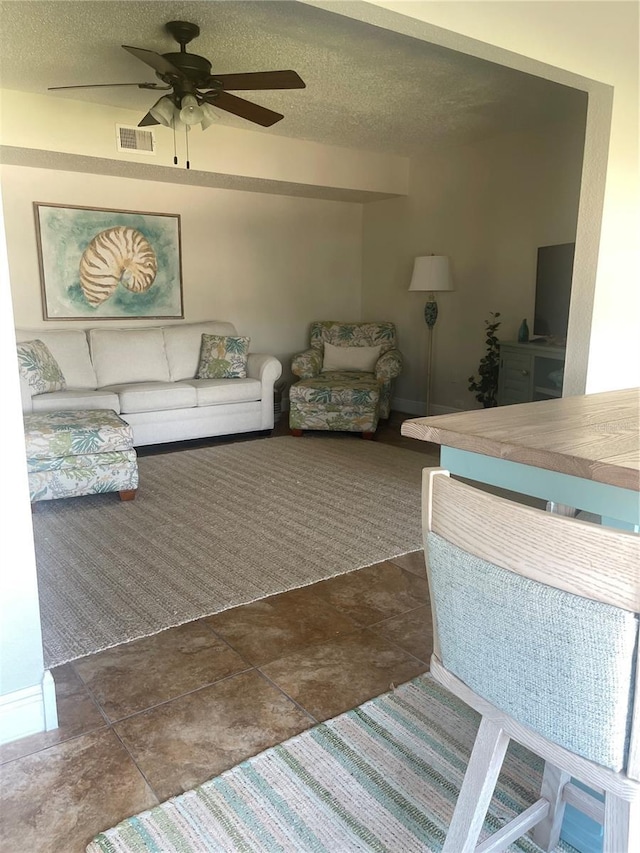 living room featuring dark colored carpet, ceiling fan, and a textured ceiling