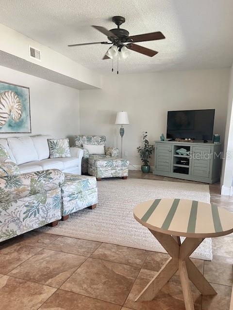 living room with tile patterned flooring, a textured ceiling, and ceiling fan