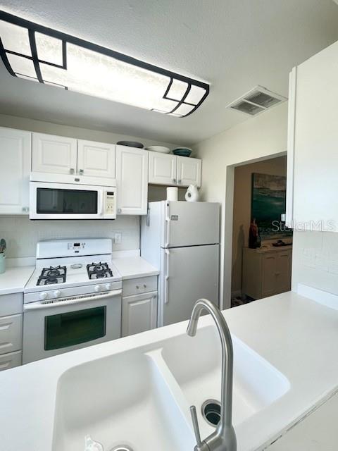 kitchen featuring white appliances, white cabinetry, and sink