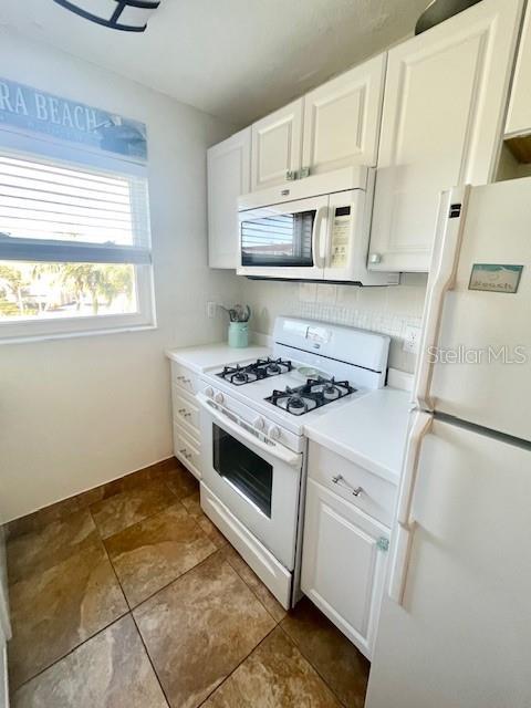 kitchen featuring tile patterned flooring, white cabinets, and white appliances