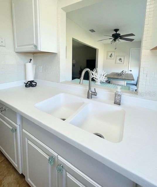 kitchen with ceiling fan, sink, tasteful backsplash, tile patterned floors, and white cabinets