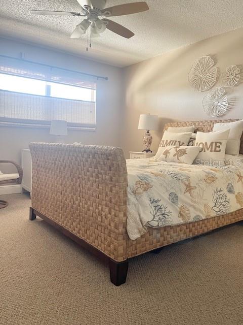 bedroom with carpet, a textured ceiling, and ceiling fan