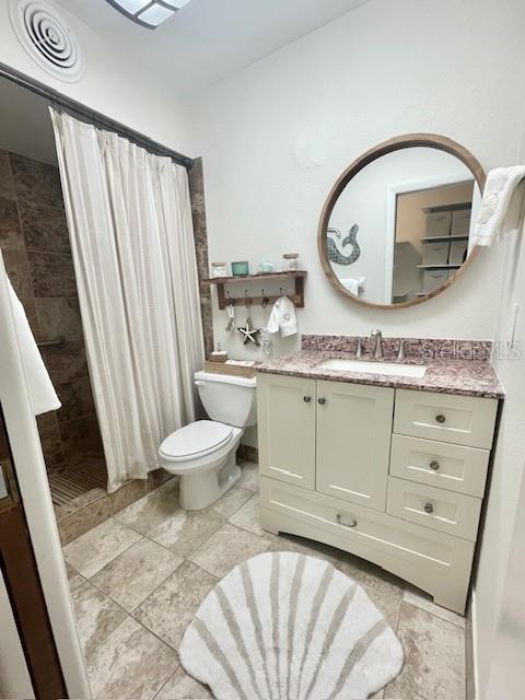 bathroom featuring a shower with shower curtain, vanity, toilet, and tile patterned flooring