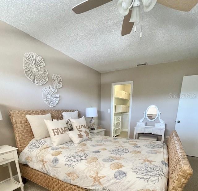 bedroom with carpet, a textured ceiling, ceiling fan, a spacious closet, and a closet