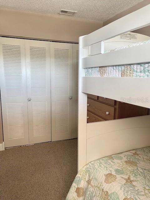 unfurnished bedroom featuring dark carpet, a textured ceiling, and a closet