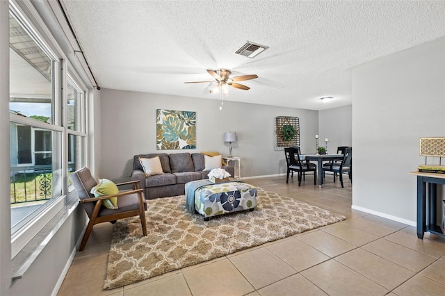 living room with ceiling fan, light tile patterned flooring, and a textured ceiling