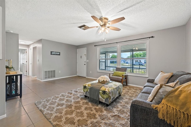 living room featuring tile patterned flooring, a textured ceiling, and ceiling fan