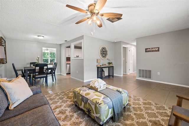 living room featuring tile patterned floors, ceiling fan, and a textured ceiling