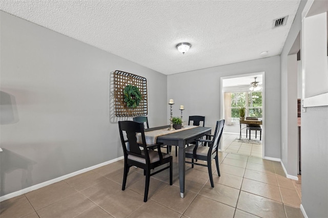 dining area with ceiling fan, light tile patterned flooring, and a textured ceiling