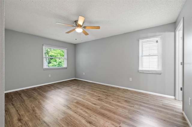 empty room with ceiling fan, a textured ceiling, and light hardwood / wood-style flooring