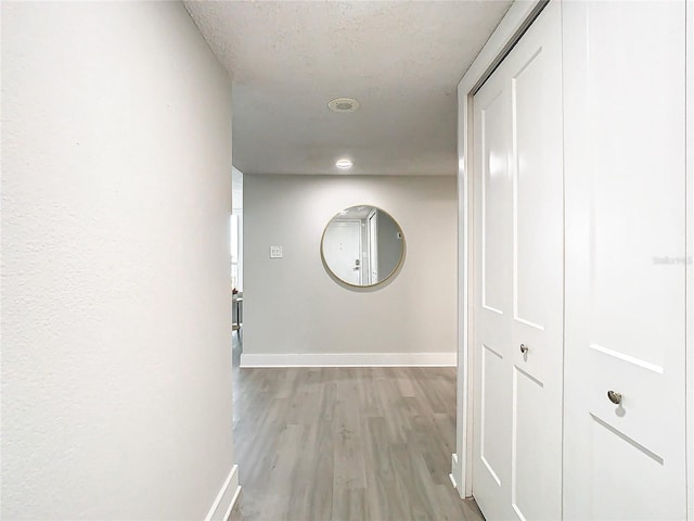 hallway featuring a textured ceiling and light hardwood / wood-style flooring