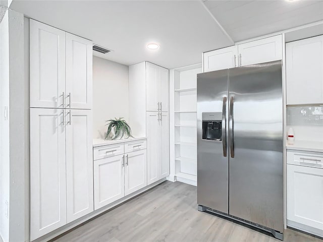 kitchen with stainless steel fridge, white cabinetry, and light hardwood / wood-style flooring