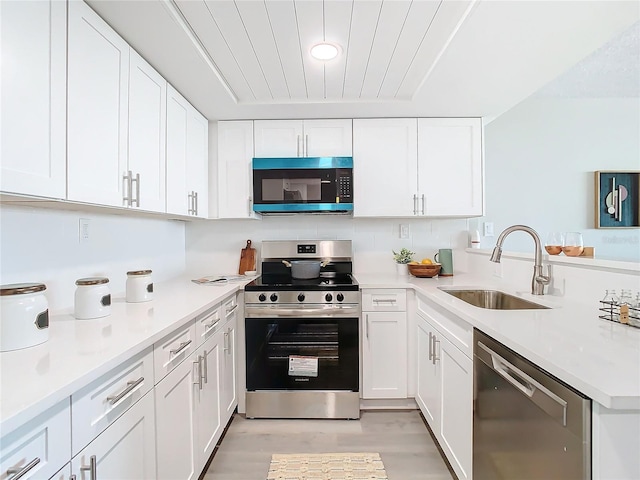 kitchen with white cabinets, sink, stainless steel appliances, and light hardwood / wood-style flooring