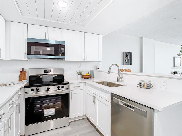 kitchen featuring white cabinets, sink, light hardwood / wood-style floors, kitchen peninsula, and stainless steel appliances