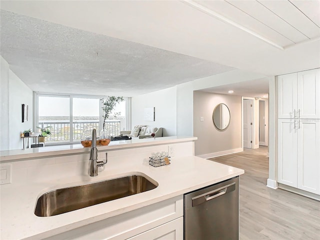 kitchen featuring light wood-type flooring, white cabinets, a textured ceiling, sink, and dishwasher