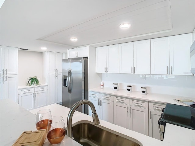 kitchen featuring white cabinets, electric range, stainless steel fridge with ice dispenser, and sink