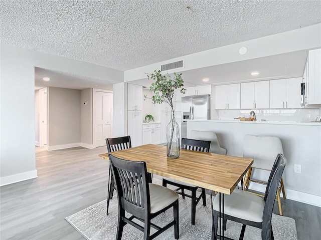 dining room with a textured ceiling and light wood-type flooring