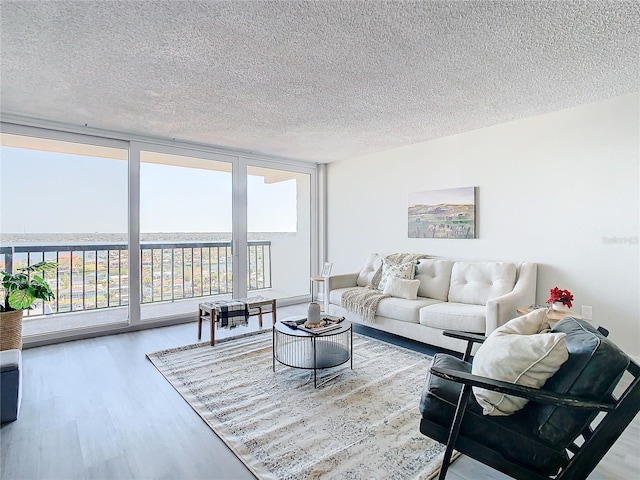 living room with expansive windows, a water view, wood-type flooring, and a textured ceiling