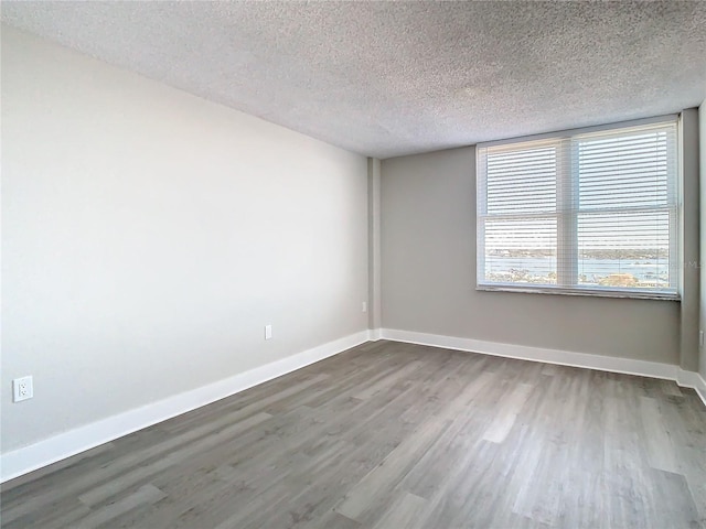 empty room with dark wood-type flooring and a textured ceiling