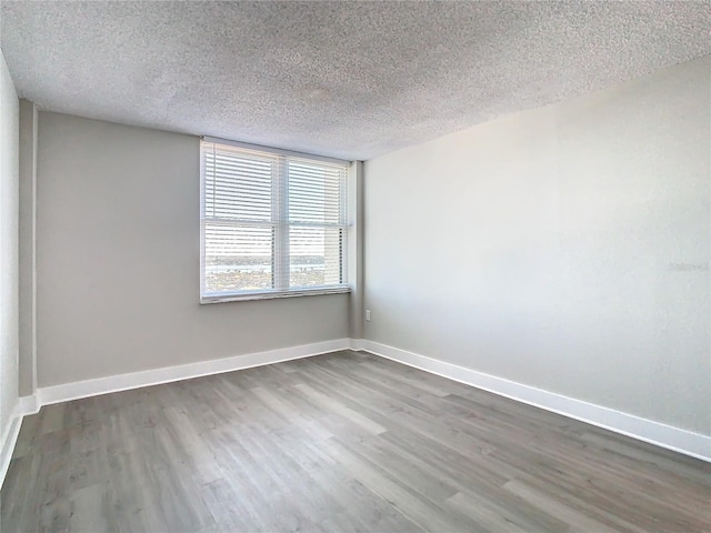 empty room with a textured ceiling and dark hardwood / wood-style floors