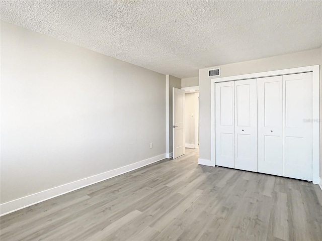 unfurnished bedroom with a closet, a textured ceiling, and light wood-type flooring