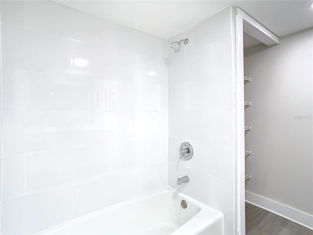 bathroom featuring wood-type flooring and tiled shower / bath