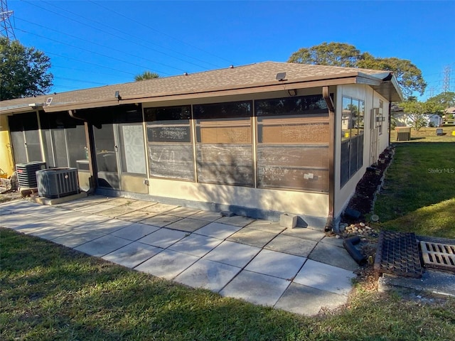 back of property featuring central air condition unit, a patio area, a lawn, and a sunroom