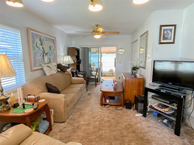 living room featuring ceiling fan, light carpet, and a textured ceiling