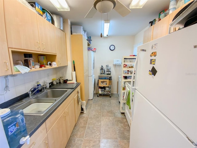 kitchen with white fridge, light brown cabinetry, stacked washer / drying machine, backsplash, and sink