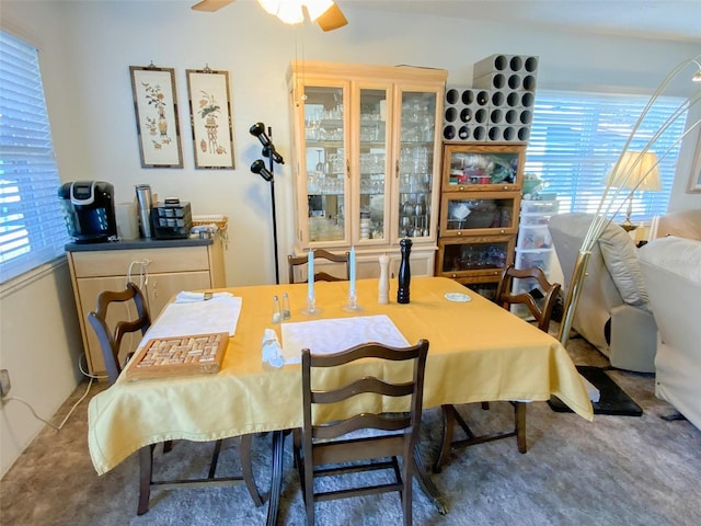 carpeted dining room with ceiling fan and plenty of natural light