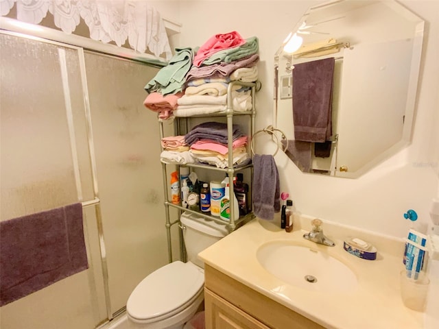 bathroom featuring toilet, a shower with door, and vanity