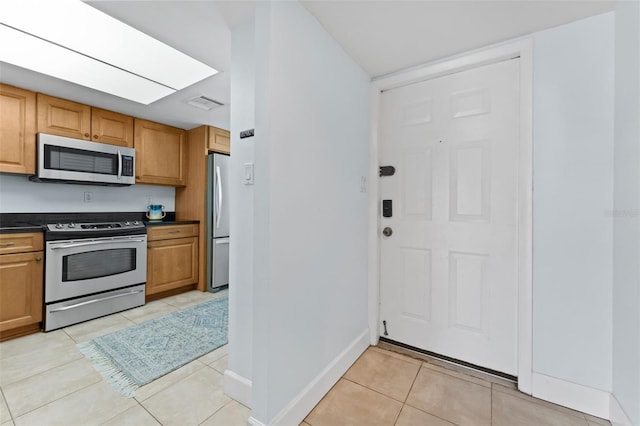 201 W Laurel St Unit 503, Tampa, FL 33602 - kitchen featuring stainless steel appliances, dark countertops, light tile patterned flooring, baseboards, and brown cabinets