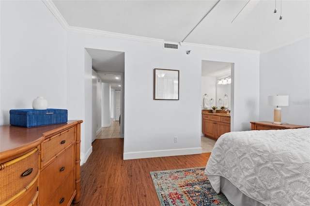 bedroom featuring ensuite bathroom, light hardwood / wood-style flooring, ceiling fan, and ornamental molding