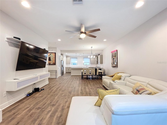 living room with hardwood / wood-style floors and ceiling fan with notable chandelier