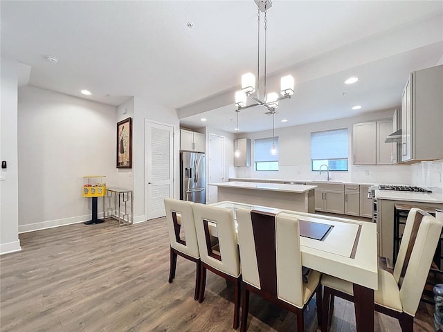 dining space featuring sink, wood-type flooring, and a notable chandelier