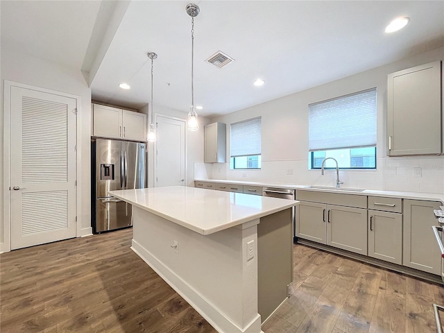 kitchen with sink, hanging light fixtures, hardwood / wood-style flooring, a kitchen island, and stainless steel appliances