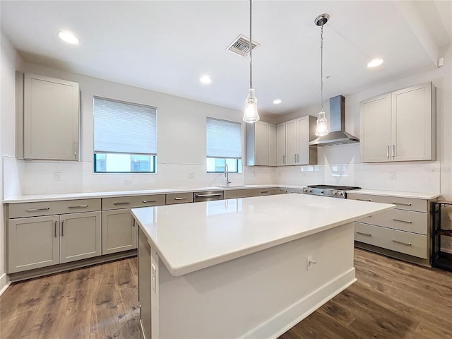 kitchen with sink, wall chimney exhaust hood, dark hardwood / wood-style flooring, pendant lighting, and a kitchen island