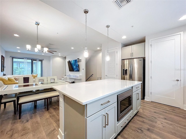 kitchen with pendant lighting, a center island, hardwood / wood-style flooring, ceiling fan, and appliances with stainless steel finishes