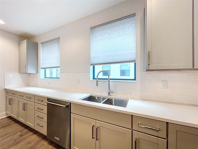 kitchen featuring sink, tasteful backsplash, stainless steel dishwasher, dark hardwood / wood-style floors, and gray cabinets