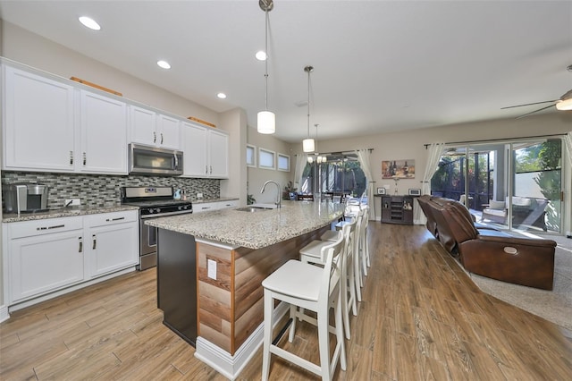 kitchen featuring a center island with sink, sink, light hardwood / wood-style flooring, appliances with stainless steel finishes, and white cabinetry