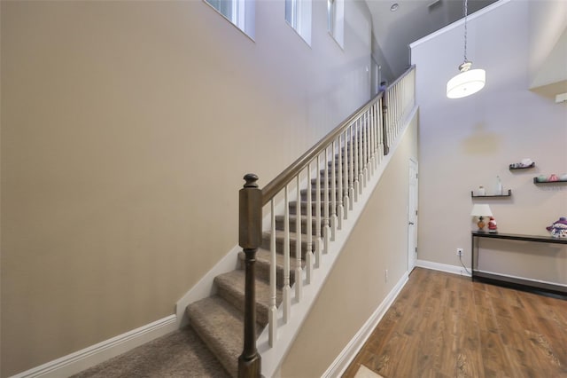 stairs with hardwood / wood-style flooring and a towering ceiling